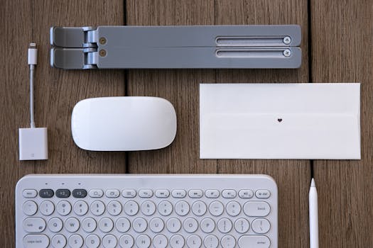 Flat lay of modern tech peripherals and stationery on a wooden desk.